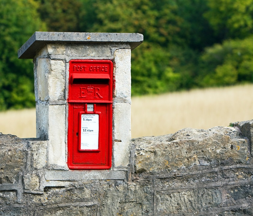 A charming old red post-box which is housed in a stone wall.