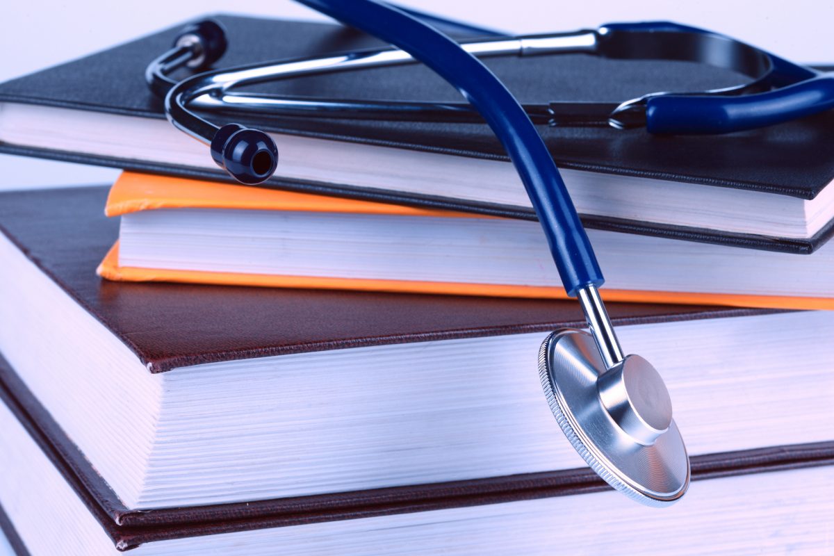 A stethoscope on top of a pile of several books
