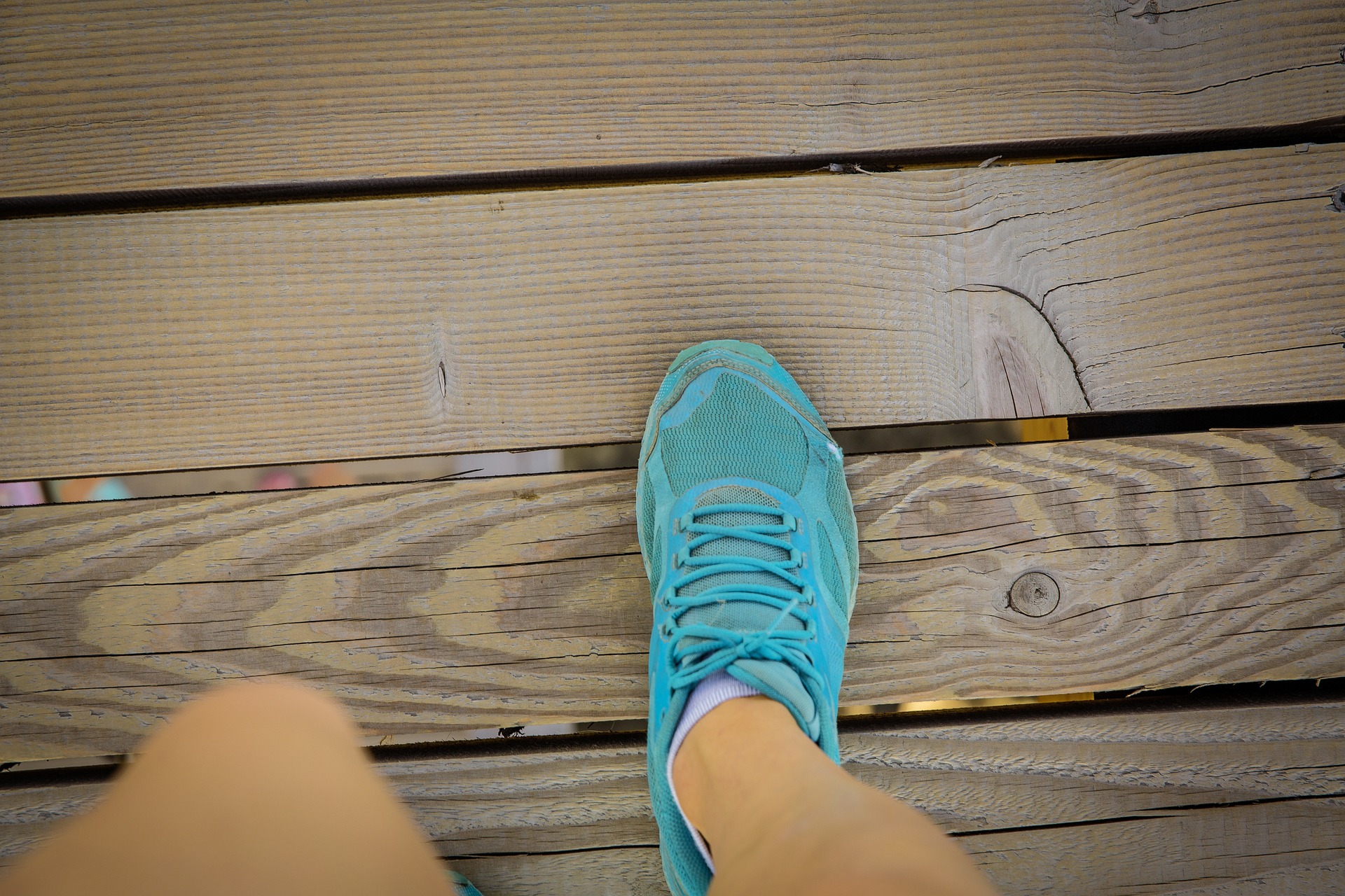 Foot in a blue trainer walking over a wooden surface