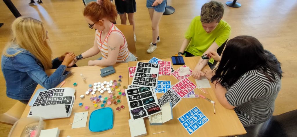 People have temporary tattoos placed on their arms as part of a charity event 