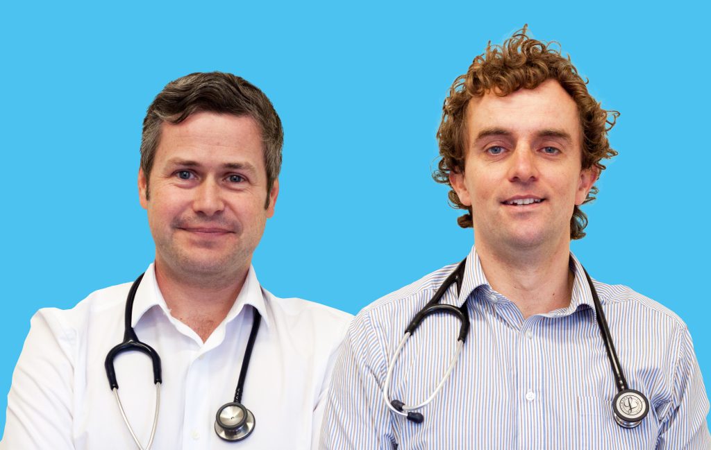 A photo of Dr Ed Cantelo and Dr Tommy Perkins of Medics' Money, against a blue background. They are light-skinned men wearing collared shirts with stethoscopes around their necks.