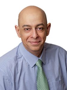 Photo of Robin Banerji, RMBF Trustee. He is a brown-skinned man with a bald head. He is wearing a blue collared shirt and a green tie.