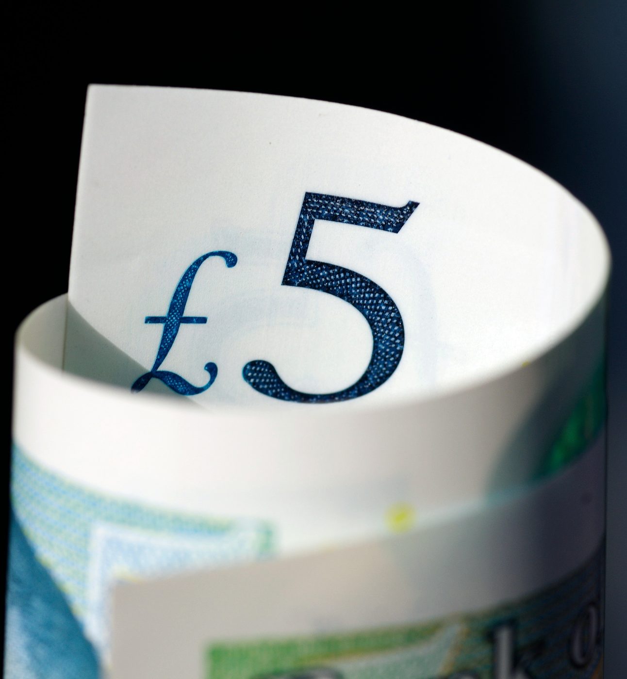 Close up photo of a rolled-up banknote, with the text 