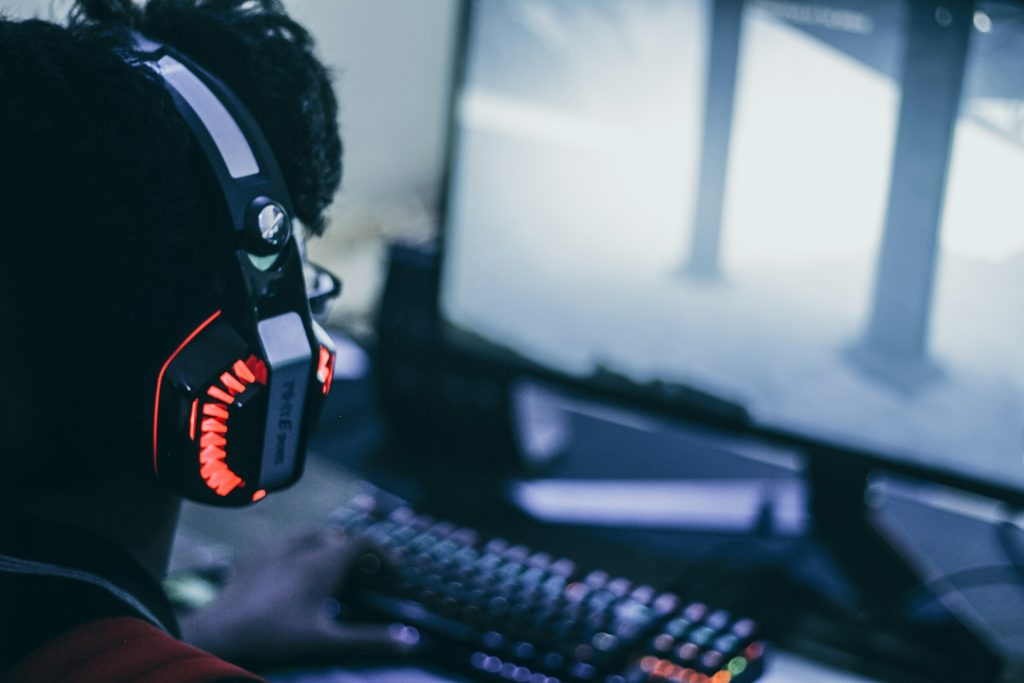 Man with gaming headphones on, looking at a screen