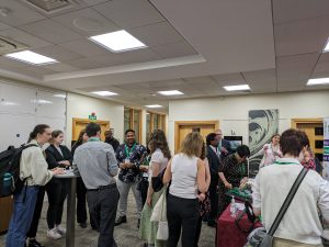 A group of conference attendees are mingling and chatting in a lobby.