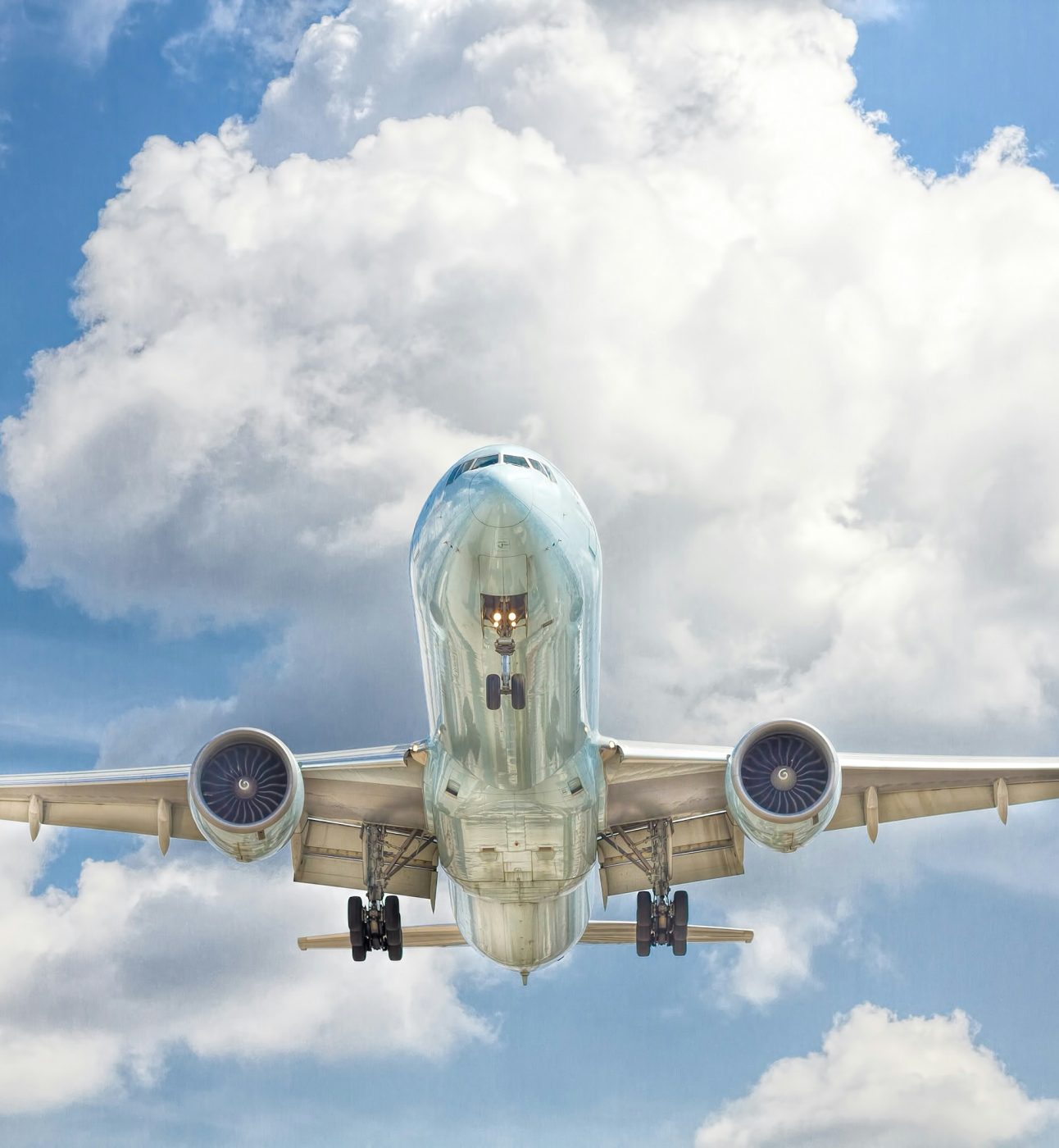 A photo of a large aeroplane in flight, a cloudy blue sky behind.