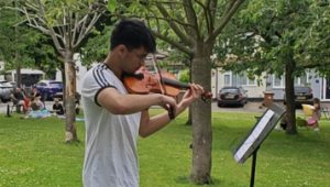 Poorwa playing the violin in a field outside