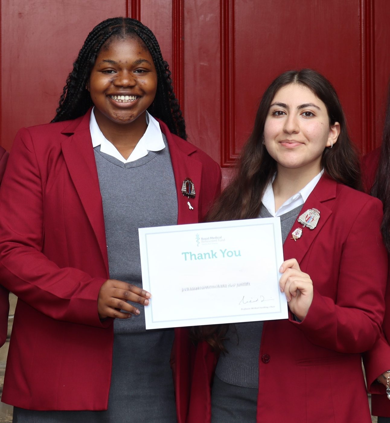 Two female students holding an RMBF certificate, smiling at the camera