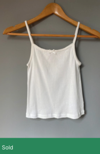 Photo of a white vest top with the word "Sold" underneath