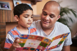 A father and son reading a book together.